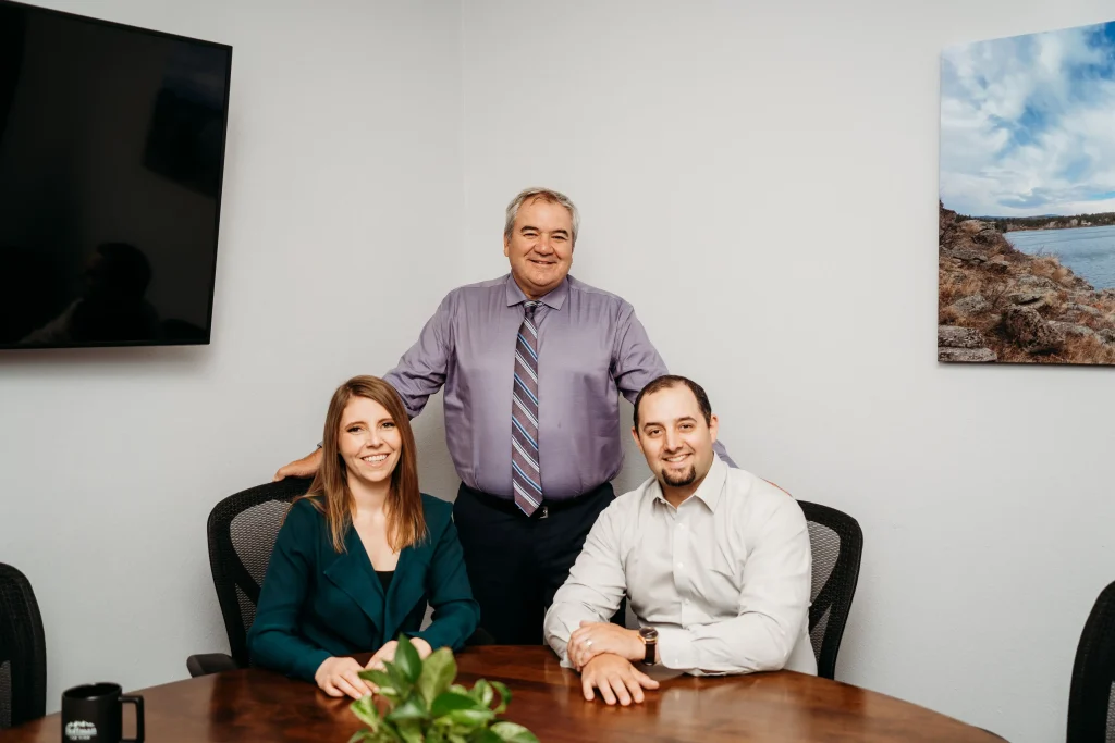 Hoffman Law attorneys Ryan Cordsen, Brad Hoffman, and Elyse Ritchie sitting in the conference room desk together
