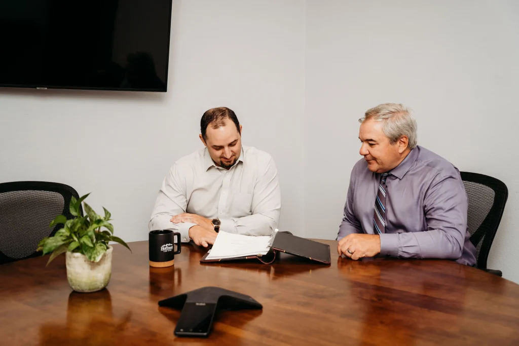 Attorneys, Ryan Cordsen and Brad Hoffman, sitting at a conference room desk discussing legal matters in the office of Hoffman Law in Fort Collins Colorado.