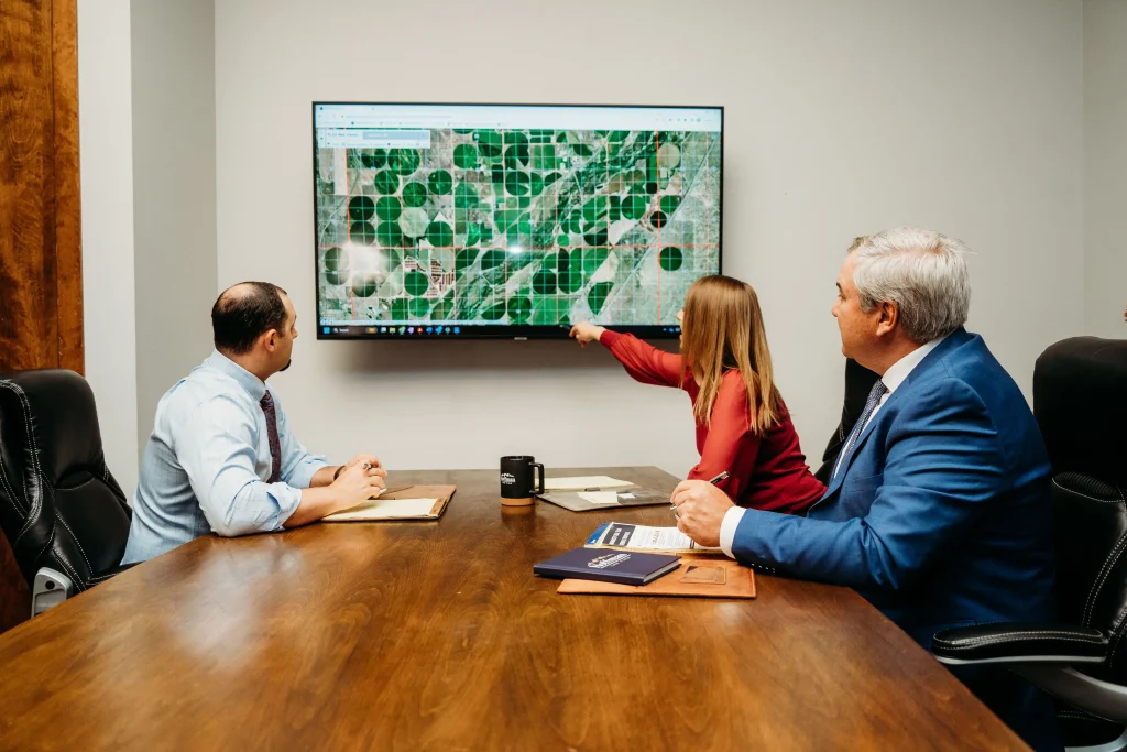 Attorneys Elyse Ritchie, Ryan Cordsen, and Brad Hoffman sitting at a conference room desk as Elyse goes over a map on the screen.