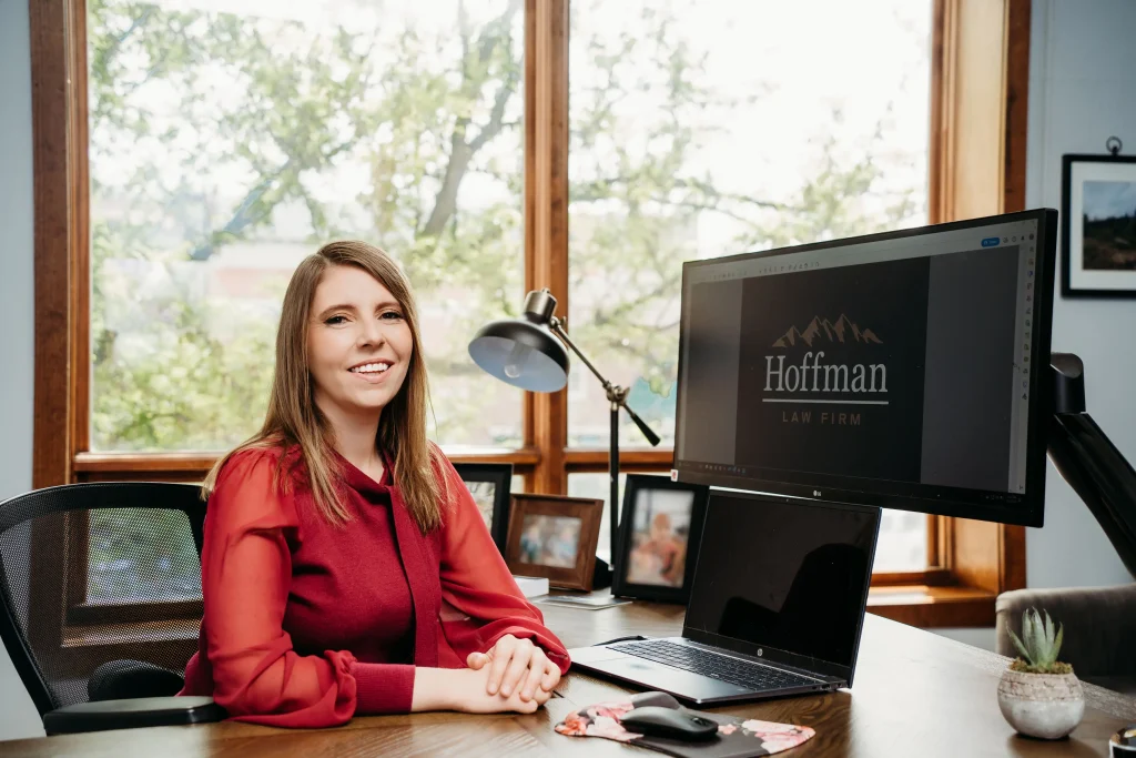 Elyse Ritchie, attorney at Hoffman Law in Fort Collins, sitting at a desk with her computer turned on reading "Hoffman Law"